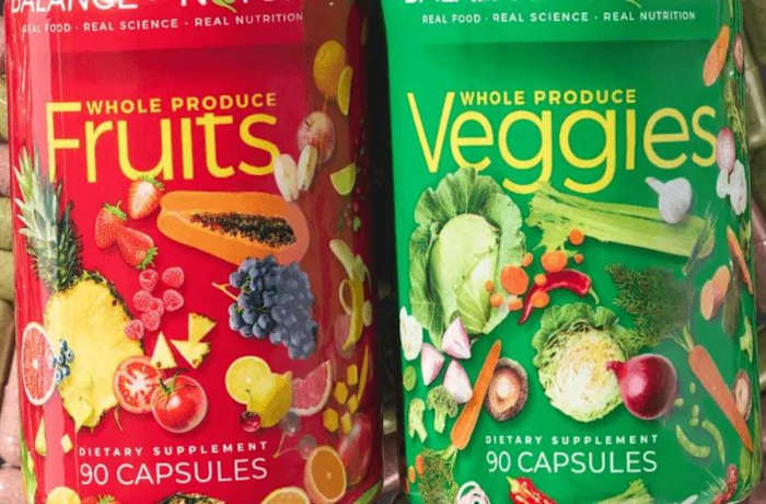 A bright red container of Balance of Nature Fruits supplement next to a bright green container of Balance of Nature Veggies supplement